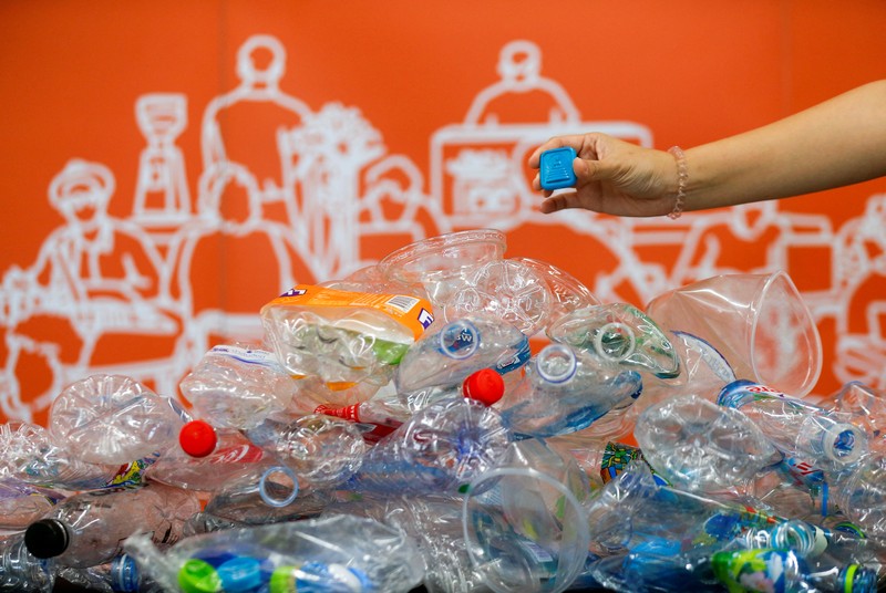 THAILAND-ENVIRONMENT/PLASTIC-AMULETS A woman shows an amulet, above 1kg of plastic bottles, which was made from 1kg of trash such as plastic bags, bottle caps, milk cotton and fishing nets, at Bangkok Design Week festival, in Bangkok, Thailand January 12, 2022. Picture taken January 12, 2022. REUTERS/Soe Zeya Tun