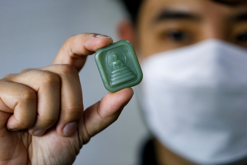 A woman shows an amulet, above 1kg of plastic bottles, which was made from 1kg of trash such as plastic bags, bottle caps, milk cotton and fishing nets, at Bangkok Design Week festival, in Bangkok, Thailand January 12, 2022. Picture taken January 12, 2022. REUTERS/Soe Zeya Tun