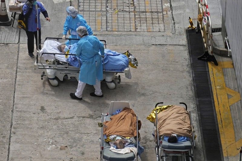 Patients lie on hospital beds as they wait at a temporary holding area outside Caritas Medical Centre in Hong Kong Wednesday, Feb.16, 2022. There was visible evidence that Hong Kong hospitals were becoming overwhelmed by the latest COVID surge, with patients on stretchers and in tents being seen to by medical personnel on Wednesday outside the Caritas hospital. (AP Photo Vincent Yu)