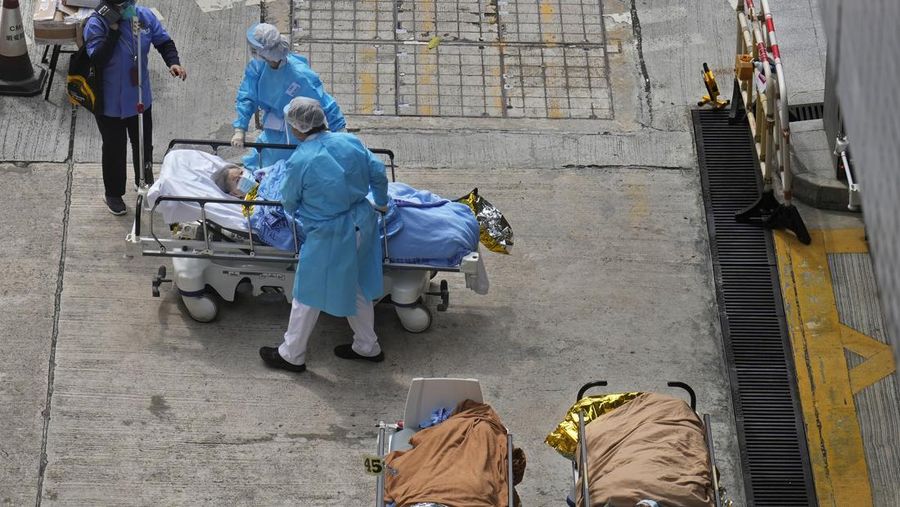 Patients lie on hospital beds as they wait at a temporary holding area outside Caritas Medical Centre in Hong Kong Wednesday, Feb.16, 2022. There was visible evidence that Hong Kong hospitals were becoming overwhelmed by the latest COVID surge, with patients on stretchers and in tents being seen to by medical personnel on Wednesday outside the Caritas hospital. (AP Photo Vincent Yu)