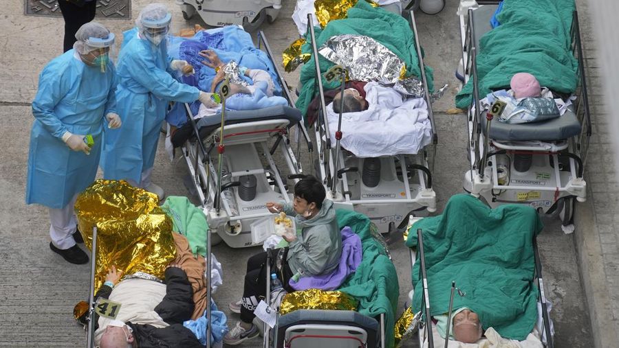 Patients lie on hospital beds as they wait at a temporary holding area outside Caritas Medical Centre in Hong Kong Wednesday, Feb.16, 2022. There was visible evidence that Hong Kong hospitals were becoming overwhelmed by the latest COVID surge, with patients on stretchers and in tents being seen to by medical personnel on Wednesday outside the Caritas hospital. (AP Photo Vincent Yu)