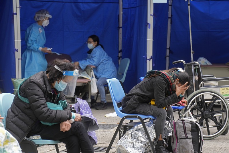 Patients lie on hospital beds as they wait at a temporary holding area outside Caritas Medical Centre in Hong Kong Wednesday, Feb.16, 2022. There was visible evidence that Hong Kong hospitals were becoming overwhelmed by the latest COVID surge, with patients on stretchers and in tents being seen to by medical personnel on Wednesday outside the Caritas hospital. (AP Photo Vincent Yu)