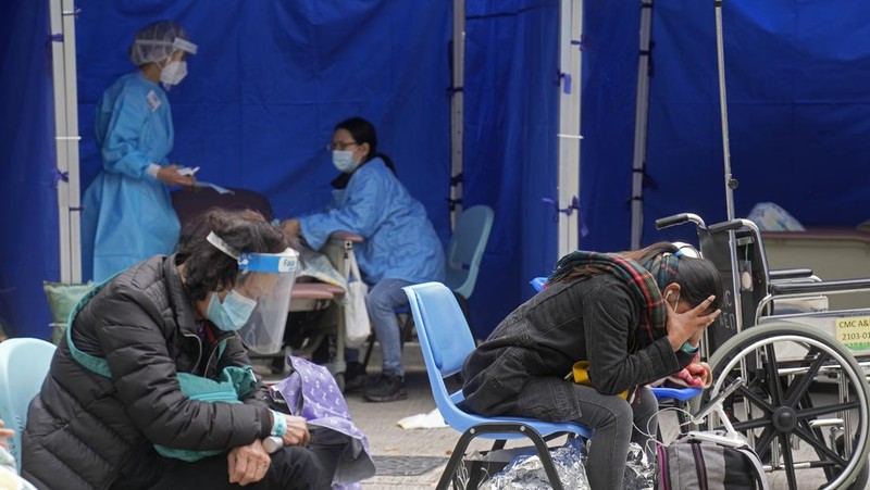 Patients lie on hospital beds as they wait at a temporary holding area outside Caritas Medical Centre in Hong Kong Wednesday, Feb.16, 2022. There was visible evidence that Hong Kong hospitals were becoming overwhelmed by the latest COVID surge, with patients on stretchers and in tents being seen to by medical personnel on Wednesday outside the Caritas hospital. (AP Photo Vincent Yu)