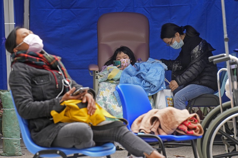 Patients lie on hospital beds as they wait at a temporary holding area outside Caritas Medical Centre in Hong Kong Wednesday, Feb.16, 2022. There was visible evidence that Hong Kong hospitals were becoming overwhelmed by the latest COVID surge, with patients on stretchers and in tents being seen to by medical personnel on Wednesday outside the Caritas hospital. (AP Photo Vincent Yu)