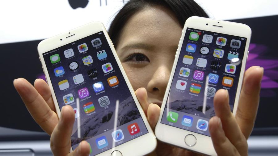 FILE - In this Sept 19, 2014 file photo, a customer shows off the new Apple iPhone 6, right, and 6 Plus at a store in Tokyo. Apple sold 61 million iPhones in the first three months of 2015, or 40 percent more than in the same period a year ago. That represented about two-thirds of its $58 billion in revenue. (AP Photo/Shizuo Kambayashi, File)