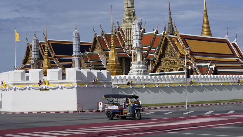 A motor-tricycle, or Tuk Tuk drives past Grand Palace in Bangkok, Thailand on Aug. 3, 2021. As Thailand battles a punishing COVID-19 surge with nearly 20,000 new cases every day, people who depend on tourism struggle in what was one of the most-visited cities in the world, with 20 million visitors in the year before the pandemic. (AP Photo/Sakchai Lalit)