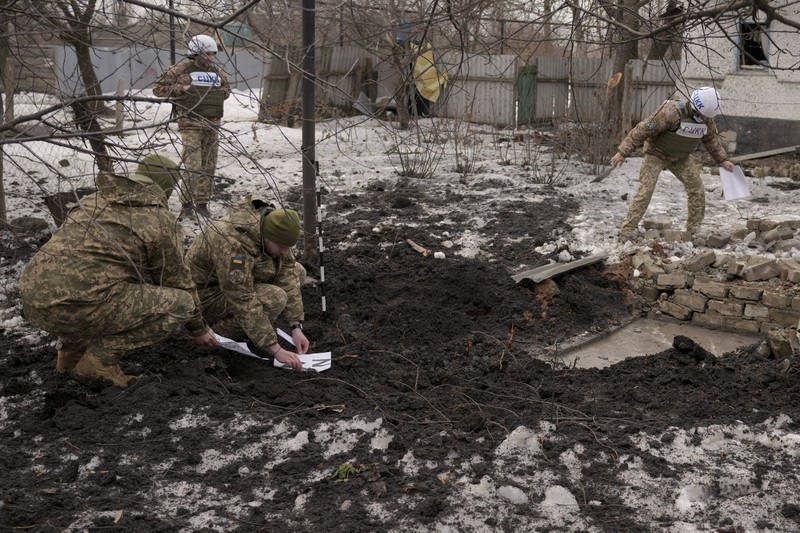 Seorang penduduk setempat berdiri di dekat sebuah lubang di dinding di dalam ruang kelas taman kanak-kanak, yang menurut pejabat militer Ukraina, dirusak oleh penembakan, di Stanytsia Luhanska di wilayah Luhansk, Ukraina, Kamis (17/2/2022). (REUTERS/Carlos Barria)