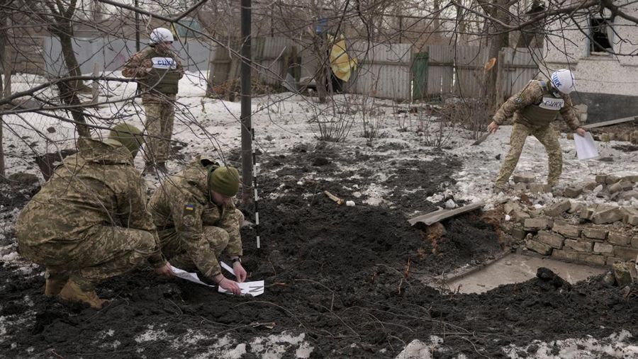 Anggota Pusat Gabungan untuk Kontrol dan Koordinasi tentang gencatan senjata garis demarkasi, atau JCCC, mengamati lubang peluru artileri yang mendarat di dekat sebuah sekolah di Vrubivka di wilayah Luhansk, Ukraina timur, Kamis (17/2/2022).  Presiden AS Joe Biden memperingatkan bahwa Rusia masih bisa menyerang Ukraina dalam beberapa hari dan Rusia mengusir diplomat No. 2 di Kedutaan Besar AS di Moskow, karena ketegangan berkobar lagi dalam kebuntuan Timur-Barat terburuk dalam beberapa dekade. (AP Photo/Vadim Ghirda)