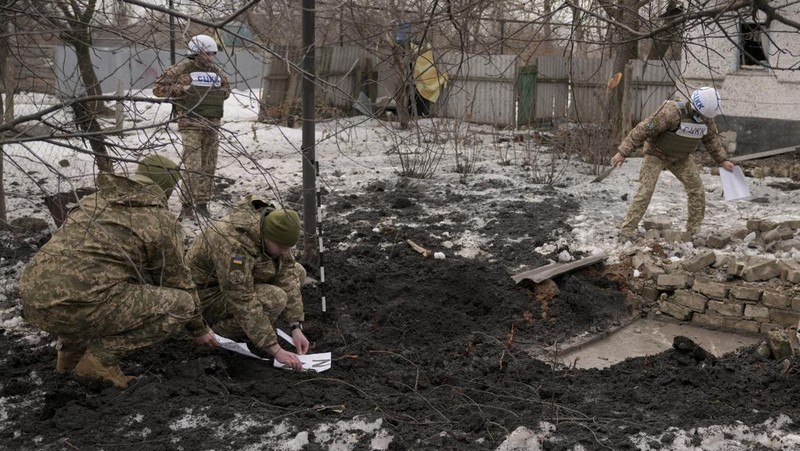 Seorang penduduk setempat berdiri di dekat sebuah lubang di dinding di dalam ruang kelas taman kanak-kanak, yang menurut pejabat militer Ukraina, dirusak oleh penembakan, di Stanytsia Luhanska di wilayah Luhansk, Ukraina, Kamis (17/2/2022). (REUTERS/Carlos Barria)