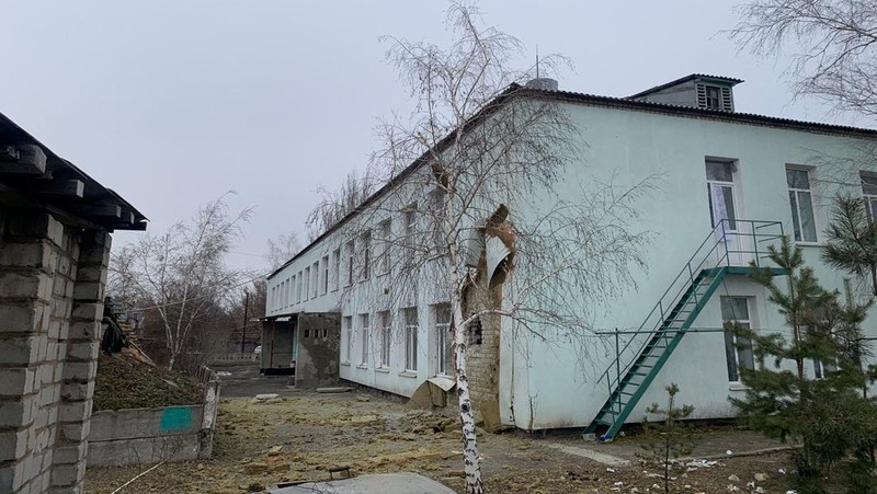 Seorang penduduk setempat berdiri di dekat sebuah lubang di dinding di dalam ruang kelas taman kanak-kanak, yang menurut pejabat militer Ukraina, dirusak oleh penembakan, di Stanytsia Luhanska di wilayah Luhansk, Ukraina, Kamis (17/2/2022). (REUTERS/Carlos Barria)