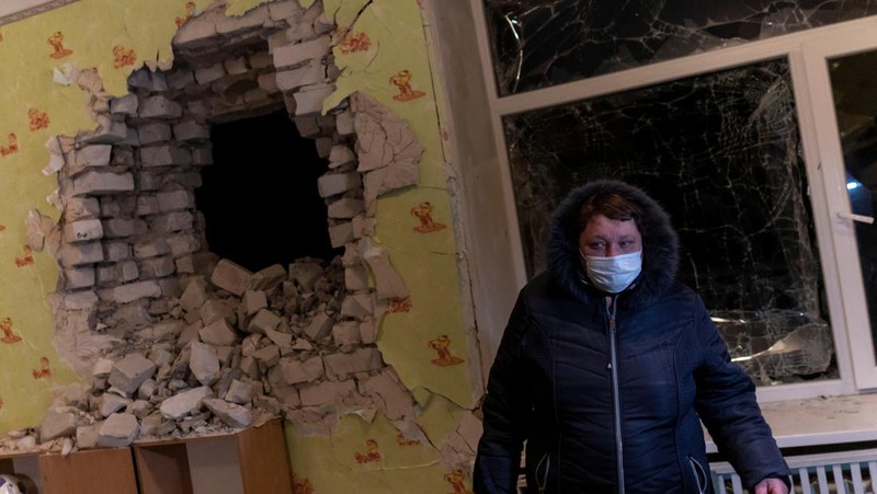 Seorang penduduk setempat berdiri di dekat sebuah lubang di dinding di dalam ruang kelas taman kanak-kanak, yang menurut pejabat militer Ukraina, dirusak oleh penembakan, di Stanytsia Luhanska di wilayah Luhansk, Ukraina, Kamis (17/2/2022). (REUTERS/Carlos Barria)