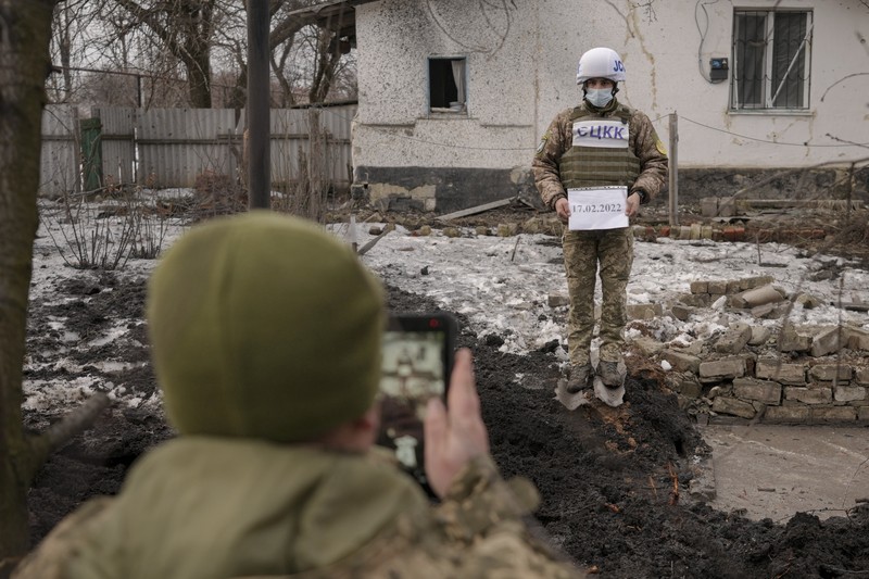 Seorang penduduk setempat berdiri di dekat sebuah lubang di dinding di dalam ruang kelas taman kanak-kanak, yang menurut pejabat militer Ukraina, dirusak oleh penembakan, di Stanytsia Luhanska di wilayah Luhansk, Ukraina, Kamis (17/2/2022). (REUTERS/Carlos Barria)