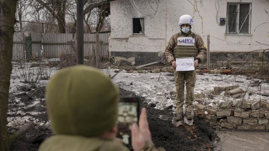 Seorang penduduk setempat berdiri di dekat sebuah lubang di dinding di dalam ruang kelas taman kanak-kanak, yang menurut pejabat militer Ukraina, dirusak oleh penembakan, di Stanytsia Luhanska di wilayah Luhansk, Ukraina, Kamis (17/2/2022). (REUTERS/Carlos Barria)