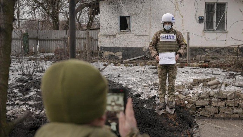 Seorang penduduk setempat berdiri di dekat sebuah lubang di dinding di dalam ruang kelas taman kanak-kanak, yang menurut pejabat militer Ukraina, dirusak oleh penembakan, di Stanytsia Luhanska di wilayah Luhansk, Ukraina, Kamis (17/2/2022). (REUTERS/Carlos Barria)