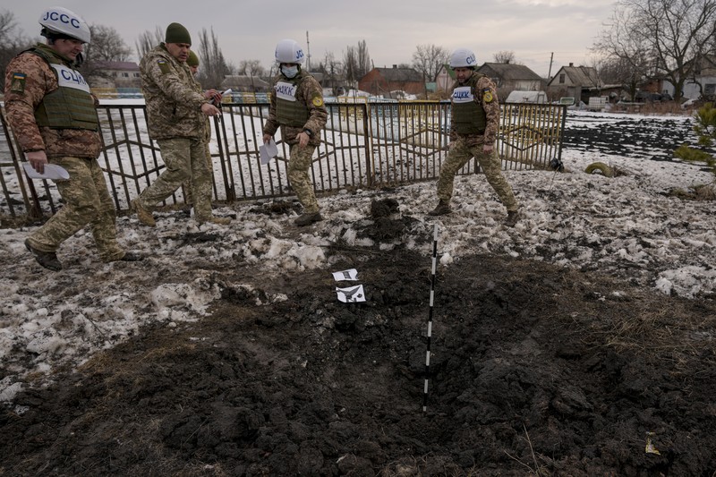 Seorang penduduk setempat berdiri di dekat sebuah lubang di dinding di dalam ruang kelas taman kanak-kanak, yang menurut pejabat militer Ukraina, dirusak oleh penembakan, di Stanytsia Luhanska di wilayah Luhansk, Ukraina, Kamis (17/2/2022). (REUTERS/Carlos Barria)