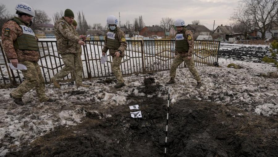 Anggota Pusat Gabungan untuk Kontrol dan Koordinasi tentang gencatan senjata garis demarkasi, atau JCCC, mengamati lubang peluru artileri yang mendarat di dekat sebuah sekolah di Vrubivka di wilayah Luhansk, Ukraina timur, Kamis (17/2/2022). Presiden AS Joe Biden memperingatkan bahwa Rusia masih bisa menyerang Ukraina dalam beberapa hari dan Rusia mengusir diplomat No. 2 di Kedutaan Besar AS di Moskow, karena ketegangan berkobar lagi dalam kebuntuan Timur-Barat terburuk dalam beberapa dekade. (AP Photo/Vadim Ghirda)