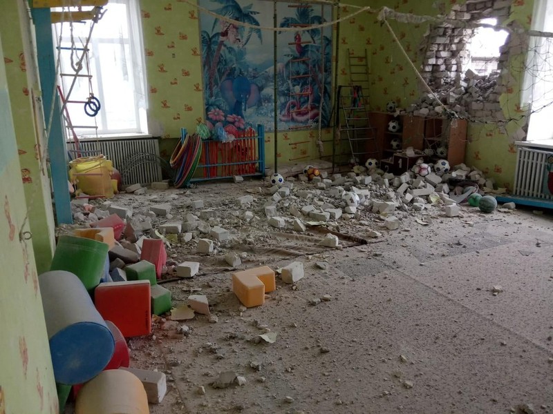 Seorang penduduk setempat berdiri di dekat sebuah lubang di dinding di dalam ruang kelas taman kanak-kanak, yang menurut pejabat militer Ukraina, dirusak oleh penembakan, di Stanytsia Luhanska di wilayah Luhansk, Ukraina, Kamis (17/2/2022). (REUTERS/Carlos Barria)