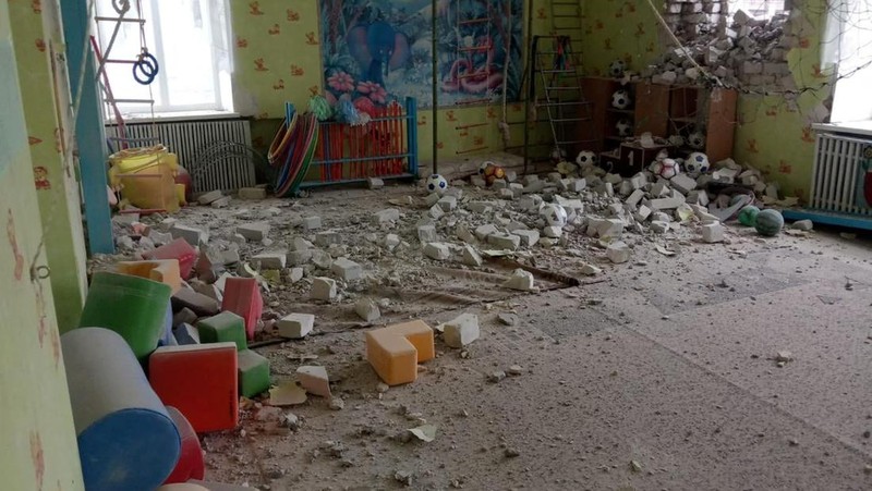 Seorang penduduk setempat berdiri di dekat sebuah lubang di dinding di dalam ruang kelas taman kanak-kanak, yang menurut pejabat militer Ukraina, dirusak oleh penembakan, di Stanytsia Luhanska di wilayah Luhansk, Ukraina, Kamis (17/2/2022). (REUTERS/Carlos Barria)