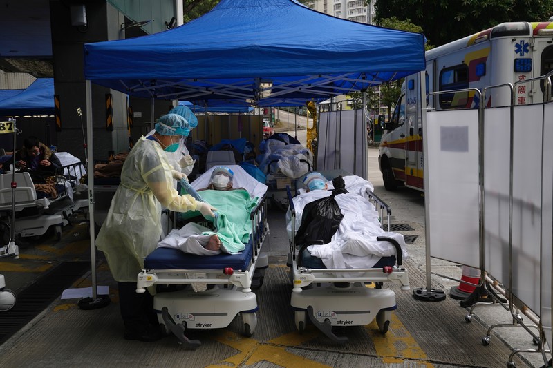Pasien berbaring di ranjang rumah sakit saat mereka menunggu di area perawatan sementara di luar Caritas Medical Center di Hong Kong, Jumat (18/2/2022). Rumah sakit Hong Kong mencapai kapasitas 90% pada hari Kamis dan fasilitas karantina sudah mencapai batasnya, kata pihak berwenang, ketika kota itu berjuang untuk memadamkan rekor jumlah kasus baru COVID-19. (AP Photo/Kin Cheung)