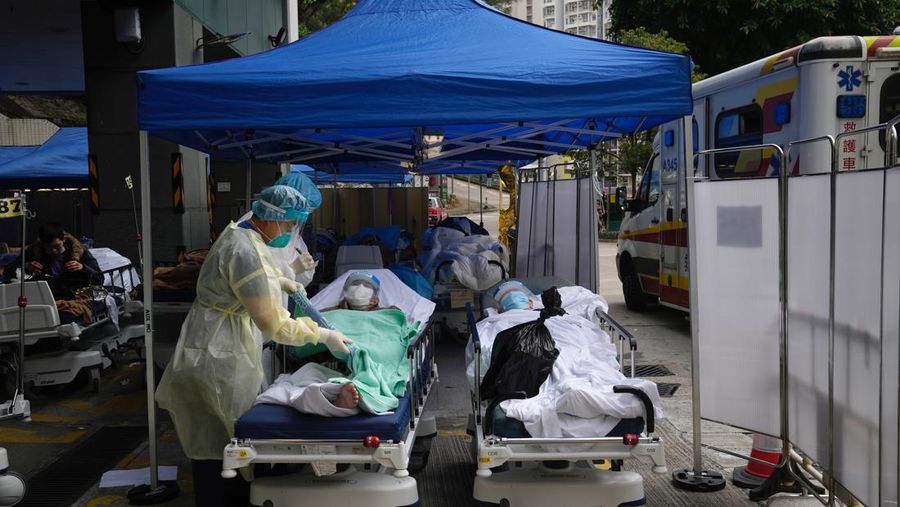 Pasien berbaring di ranjang rumah sakit saat mereka menunggu di area perawatan sementara di luar Caritas Medical Center di Hong Kong, Jumat (18/2/2022). Rumah sakit Hong Kong mencapai kapasitas 90% pada hari Kamis dan fasilitas karantina sudah mencapai batasnya, kata pihak berwenang, ketika kota itu berjuang untuk memadamkan rekor jumlah kasus baru COVID-19. (AP Photo/Kin Cheung)