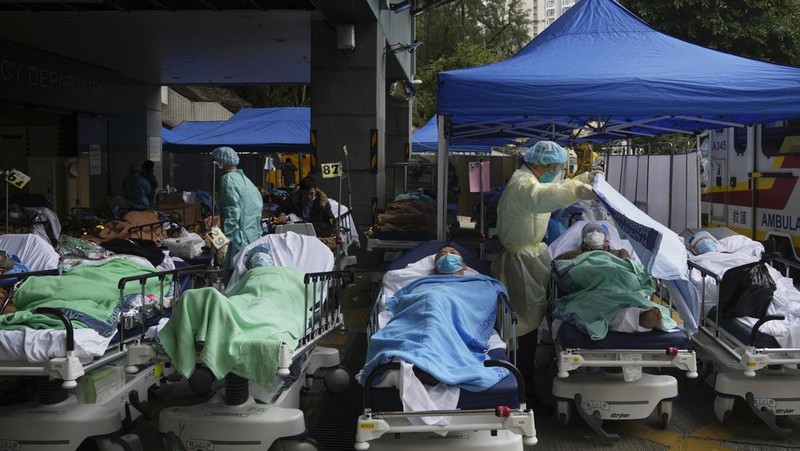 Pasien berbaring di ranjang rumah sakit saat mereka menunggu di area perawatan sementara di luar Caritas Medical Center di Hong Kong, Jumat (18/2/2022). Rumah sakit Hong Kong mencapai kapasitas 90% pada hari Kamis dan fasilitas karantina sudah mencapai batasnya, kata pihak berwenang, ketika kota itu berjuang untuk memadamkan rekor jumlah kasus baru COVID-19. (AP Photo/Kin Cheung)