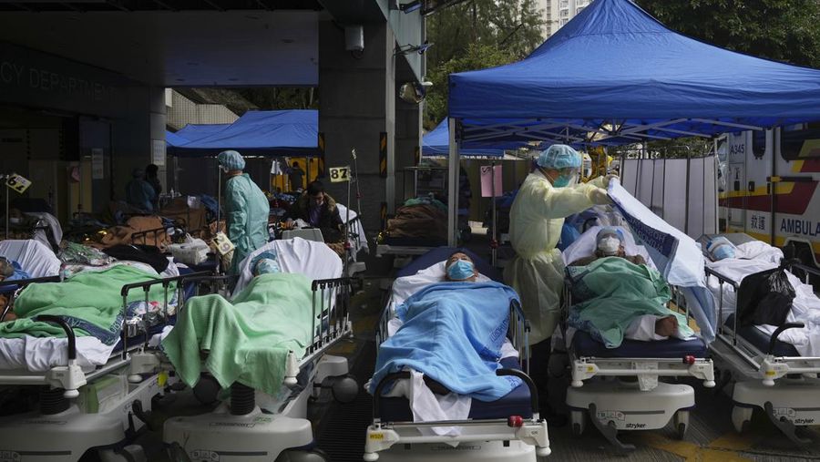 Pasien berbaring di ranjang rumah sakit saat mereka menunggu di area perawatan sementara di luar Caritas Medical Center di Hong Kong, Jumat (18/2/2022). Rumah sakit Hong Kong mencapai kapasitas 90% pada hari Kamis dan fasilitas karantina sudah mencapai batasnya, kata pihak berwenang, ketika kota itu berjuang untuk memadamkan rekor jumlah kasus baru COVID-19. (AP Photo/Kin Cheung)