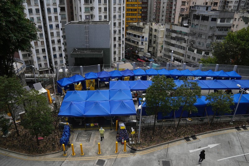 Pasien berbaring di ranjang rumah sakit saat mereka menunggu di area perawatan sementara di luar Caritas Medical Center di Hong Kong, Jumat (18/2/2022). Rumah sakit Hong Kong mencapai kapasitas 90% pada hari Kamis dan fasilitas karantina sudah mencapai batasnya, kata pihak berwenang, ketika kota itu berjuang untuk memadamkan rekor jumlah kasus baru COVID-19. (AP Photo/Kin Cheung)