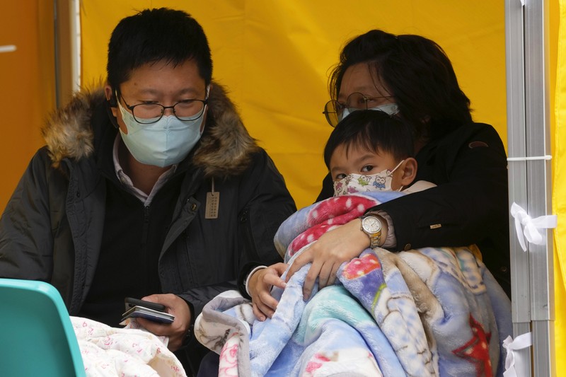Pasien berbaring di ranjang rumah sakit saat mereka menunggu di area perawatan sementara di luar Caritas Medical Center di Hong Kong, Jumat (18/2/2022). Rumah sakit Hong Kong mencapai kapasitas 90% pada hari Kamis dan fasilitas karantina sudah mencapai batasnya, kata pihak berwenang, ketika kota itu berjuang untuk memadamkan rekor jumlah kasus baru COVID-19. (AP Photo/Kin Cheung)