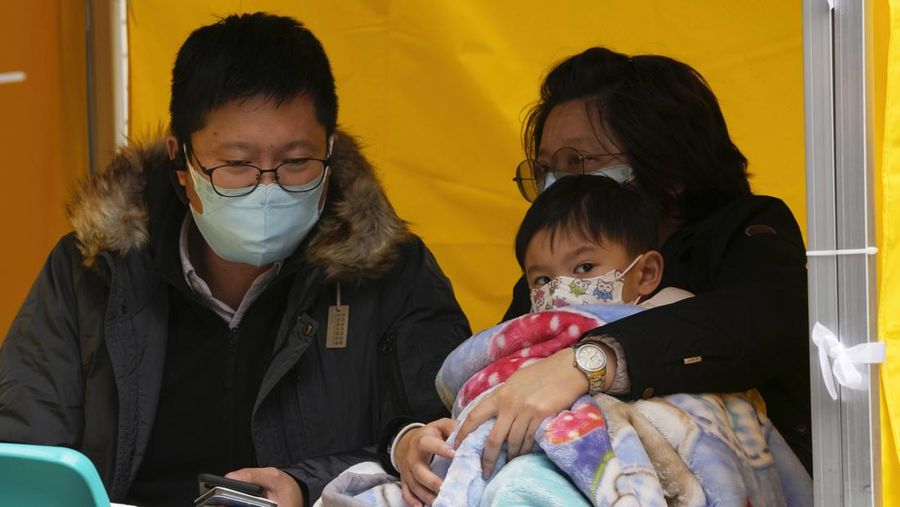 Pasien berbaring di ranjang rumah sakit saat mereka menunggu di area perawatan sementara di luar Caritas Medical Center di Hong Kong, Jumat (18/2/2022). Rumah sakit Hong Kong mencapai kapasitas 90% pada hari Kamis dan fasilitas karantina sudah mencapai batasnya, kata pihak berwenang, ketika kota itu berjuang untuk memadamkan rekor jumlah kasus baru COVID-19. (AP Photo/Kin Cheung)