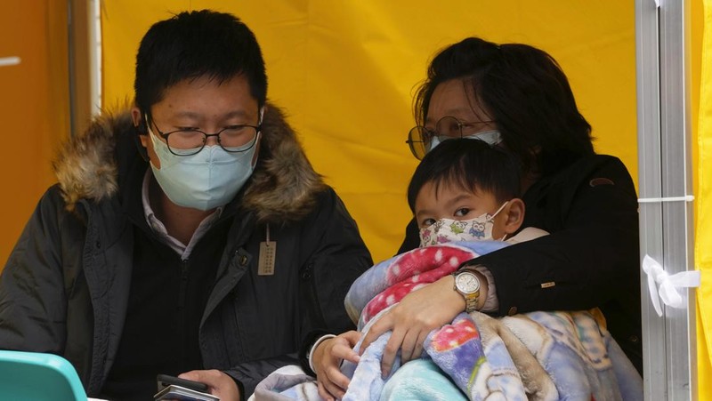 Pasien berbaring di ranjang rumah sakit saat mereka menunggu di area perawatan sementara di luar Caritas Medical Center di Hong Kong, Jumat (18/2/2022). Rumah sakit Hong Kong mencapai kapasitas 90% pada hari Kamis dan fasilitas karantina sudah mencapai batasnya, kata pihak berwenang, ketika kota itu berjuang untuk memadamkan rekor jumlah kasus baru COVID-19. (AP Photo/Kin Cheung)