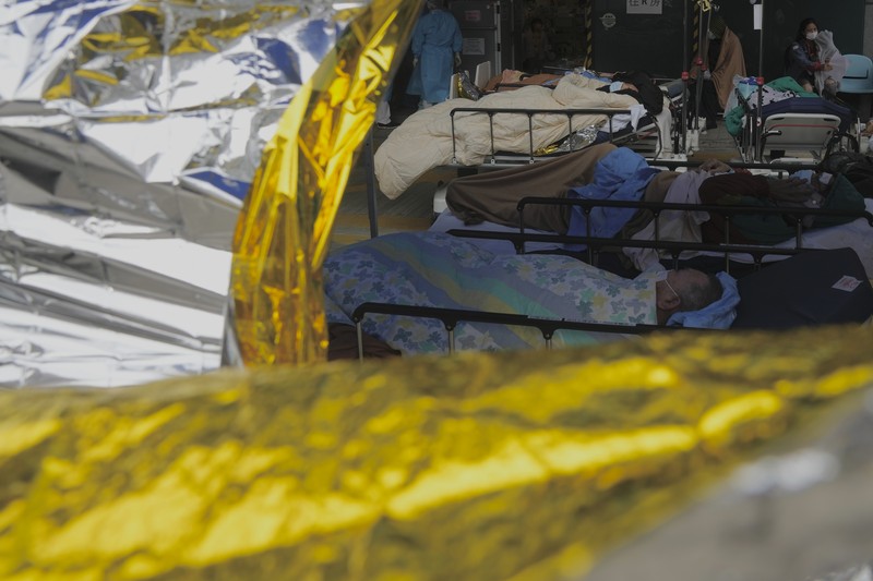 Pasien Covid-19 di Hong Kong Pasien berbaring di ranjang rumah sakit saat mereka menunggu di area perawatan sementara di luar Caritas Medical Center di Hong Kong, Jumat (18/2/2022). Rumah sakit Hong Kong mencapai kapasitas 90% pada hari Kamis dan fasilitas karantina sudah mencapai batasnya, kata pihak berwenang, ketika kota itu berjuang untuk memadamkan rekor jumlah kasus baru COVID-19. (AP Photo/Kin Cheung)