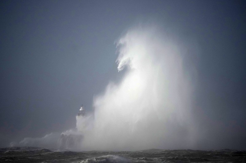 Waves crash over the Newhaven harbour breakwater and lighthouse, as Storm Eunice hits Newhaven, on the south coast of England, Friday, Feb. 18, 2022. Millions of Britons are being urged to cancel travel plans and stay indoors Friday amid fears of high winds and flying debris as the second major storm this week prompted a rare 