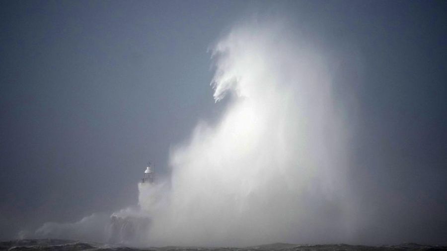 Waves crash over the Newhaven harbour breakwater and lighthouse, as Storm Eunice hits Newhaven, on the south coast of England, Friday, Feb. 18, 2022. Millions of Britons are being urged to cancel travel plans and stay indoors Friday amid fears of high winds and flying debris as the second major storm this week prompted a rare 