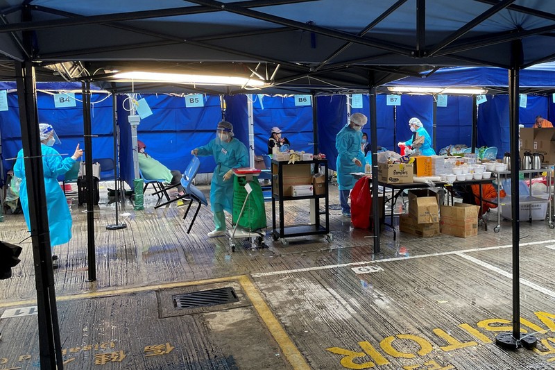 Medical workers wearing personal protective equipment (PPE), work next to patients at a makeshift treatment area outside a hospital, following the coronavirus disease (COVID-19) outbreak in Hong Kong, China February 19, 2022. REUTERS/Aleksander Solum