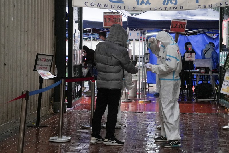 Medical workers wearing personal protective equipment (PPE), work next to patients at a makeshift treatment area outside a hospital, following the coronavirus disease (COVID-19) outbreak in Hong Kong, China February 19, 2022. REUTERS/Aleksander Solum