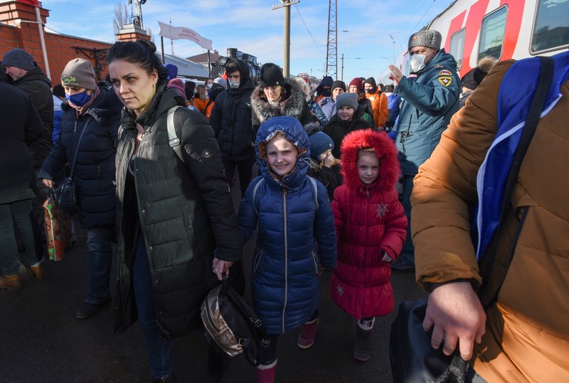 Orang-orang dari wilayah Donetsk dan Luhansk, wilayah yang dikuasai oleh pemerintah separatis pro-Rusia di Ukraina timur, berjalan kaki dari kereta api untuk dibawa ke tempat tinggal sementara di wilayah Volgograd, di stasiun kereta api di Volzhsky, wilayah Volgograd, Rusia, pada Minggu, 20 Februari 2022. (REUTERS/VLADIMIR LAVROV)