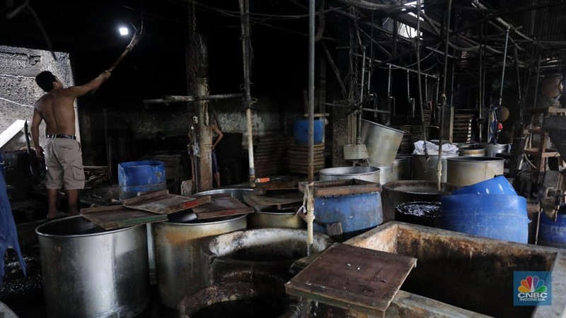Pekerja membersihkan alat pembuatan tahu di tempat kerjanya ketika melakukan mogok produksi di pabrik tahu di kawasan Duren Tiga, Jakarta Selatan, Senin (21/2/2022). (CNBC Indonesia/Andrean Kristianto)