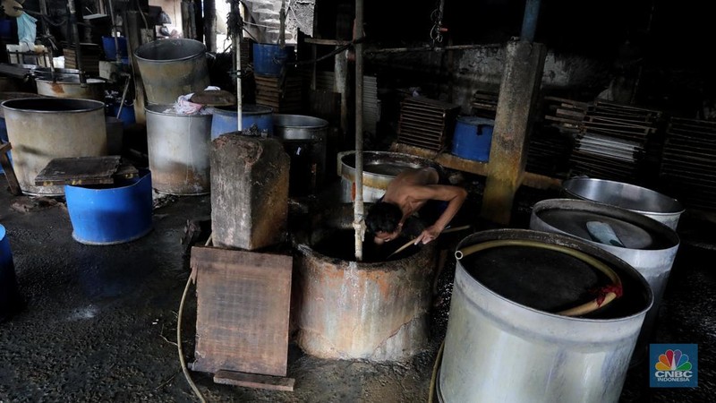 Pekerja membersihkan alat pembuatan tahu di tempat kerjanya ketika melakukan mogok produksi di pabrik tahu di kawasan Duren Tiga, Jakarta Selatan, Senin (21/2/2022). (CNBC Indonesia/Andrean Kristianto)