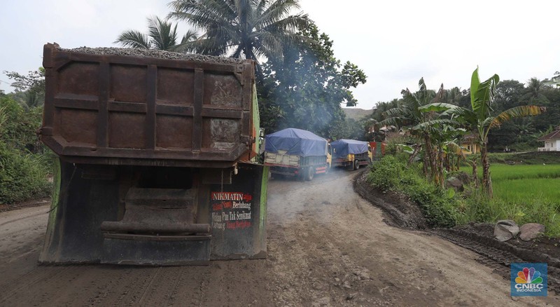 Truk pengangkut material melintas diantara gunungan tambang galian c batu andesit dan turunannya, termasuk pasir di kawasan Rumpin, Bogor, Jawa Barat, Senin, (21/2/2022). (CNBC Indonesia/Muhammad Sabki)