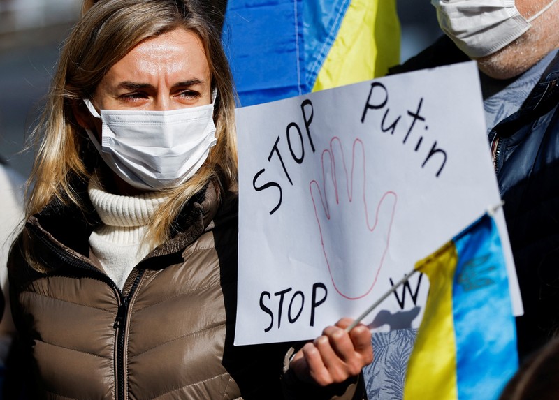 Warga Ukraina yang tinggal di Jepang berdemo memegang plakat dan bendera selama demonstrasi mengecam Rusia atas tindakannya atas Ukraina, di kedutaan Rusia di Tokyo, Jepang, Rabu (23/2/2022). (REUTERS/ISSEI KATO)