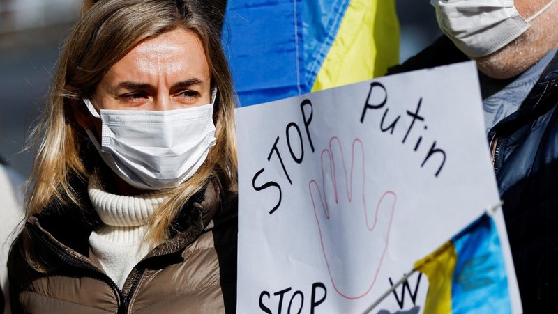 Warga Ukraina yang tinggal di Jepang berdemo memegang plakat dan bendera selama demonstrasi mengecam Rusia atas tindakannya atas Ukraina, di kedutaan Rusia di Tokyo, Jepang, Rabu (23/2/2022). (REUTERS/ISSEI KATO)