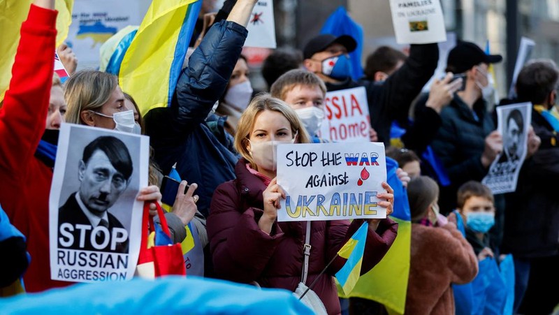 Warga Ukraina yang tinggal di Jepang berdemo memegang plakat dan bendera selama demonstrasi mengecam Rusia atas tindakannya atas Ukraina, di kedutaan Rusia di Tokyo, Jepang, Rabu (23/2/2022). (REUTERS/ISSEI KATO)