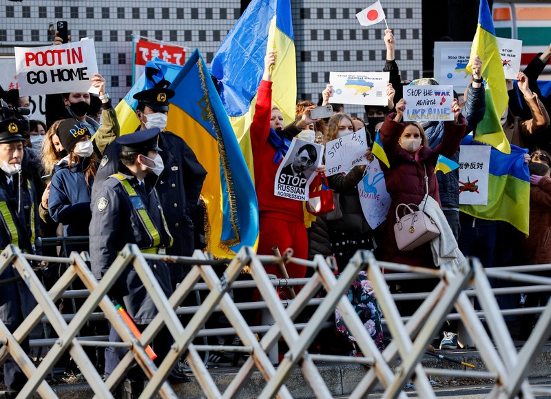 Warga Ukraina yang tinggal di Jepang berdemo memegang plakat dan bendera selama demonstrasi mengecam Rusia atas tindakannya atas Ukraina, di kedutaan Rusia di Tokyo, Jepang, Rabu (23/2/2022). (REUTERS/ISSEI KATO)