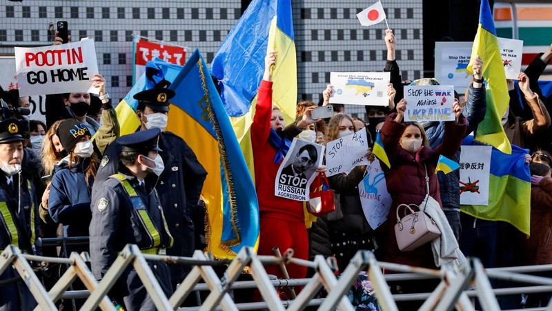 Warga Ukraina yang tinggal di Jepang berdemo memegang plakat dan bendera selama demonstrasi mengecam Rusia atas tindakannya atas Ukraina, di kedutaan Rusia di Tokyo, Jepang, Rabu (23/2/2022). (REUTERS/ISSEI KATO)