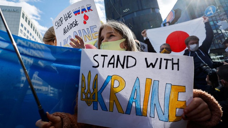 Warga Ukraina yang tinggal di Jepang berdemo memegang plakat dan bendera selama demonstrasi mengecam Rusia atas tindakannya atas Ukraina, di kedutaan Rusia di Tokyo, Jepang, Rabu (23/2/2022). (REUTERS/ISSEI KATO)
