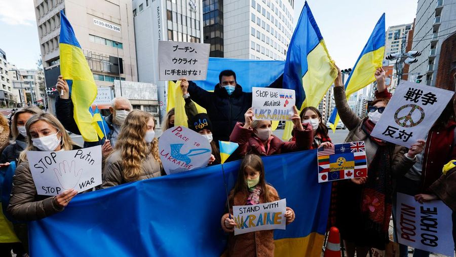 Warga Ukraina yang tinggal di Jepang berdemo memegang plakat dan bendera selama demonstrasi mengecam Rusia atas tindakannya atas Ukraina, di kedutaan Rusia di Tokyo, Jepang, Rabu (23/2/2022). (REUTERS/ISSEI KATO)