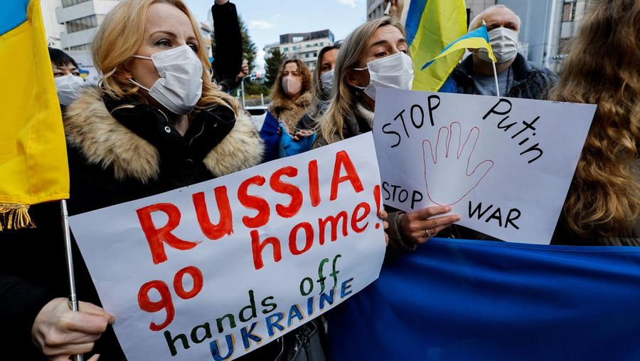 Warga Ukraina yang tinggal di Jepang berdemo memegang plakat dan bendera selama demonstrasi mengecam Rusia atas tindakannya atas Ukraina, di kedutaan Rusia di Tokyo, Jepang, Rabu (23/2/2022). (REUTERS/ISSEI KATO)