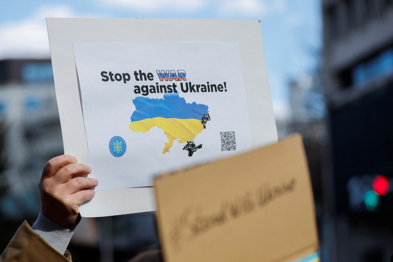 Warga Ukraina yang tinggal di Jepang berdemo memegang plakat dan bendera selama demonstrasi mengecam Rusia atas tindakannya atas Ukraina, di kedutaan Rusia di Tokyo, Jepang, Rabu (23/2/2022). (REUTERS/ISSEI KATO)
