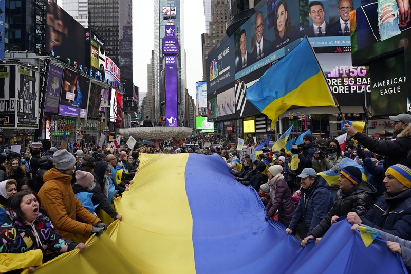 Demonstran pro-Ukraina mengibarkan bendera besar Ukraina di Times Square New York, Kamis, 24 Februari 2022. (AP/Seth Wenig)