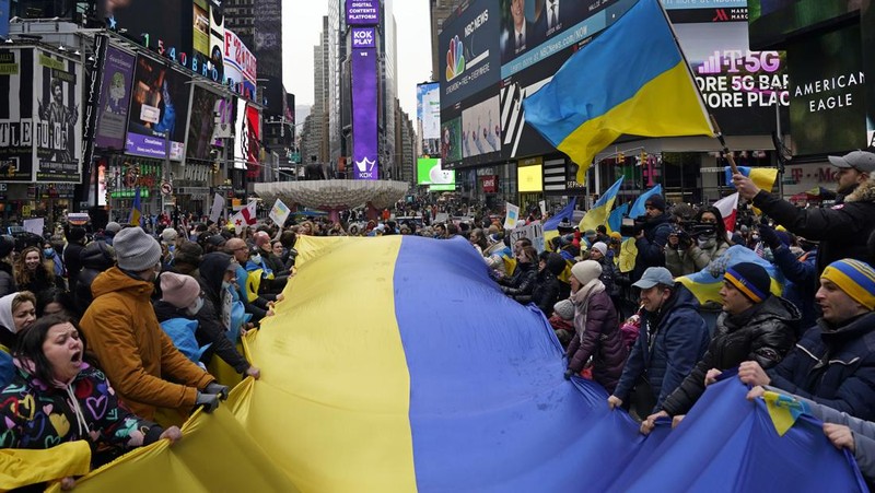 Demonstran pro-Ukraina mengibarkan bendera besar Ukraina di Times Square New York, Kamis, 24 Februari 2022. (AP/Seth Wenig)